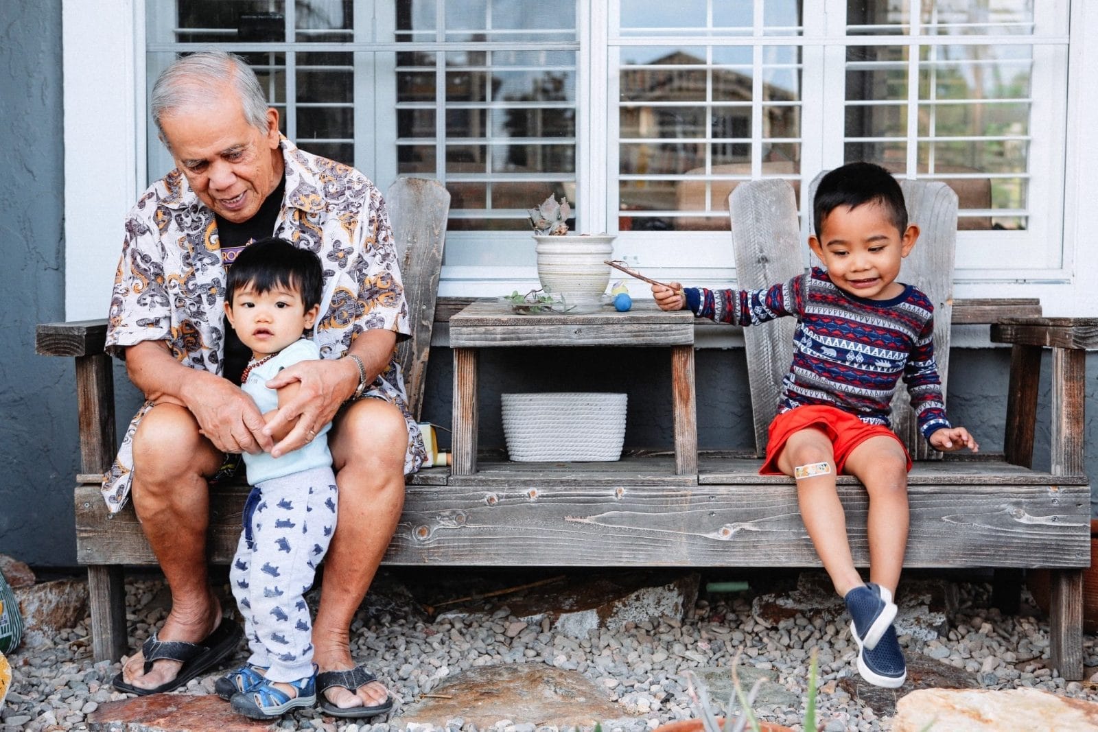 Grandparents provide free childcare, but it costs us in other ways grandpa playing with grandkids on a porch- grandparents babysitting