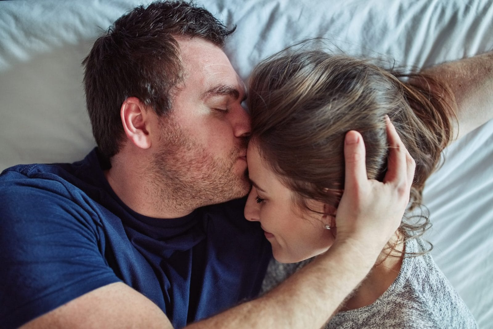 Dear husband: I know we’re both exhausted from working all day man kissing woman on the forehead