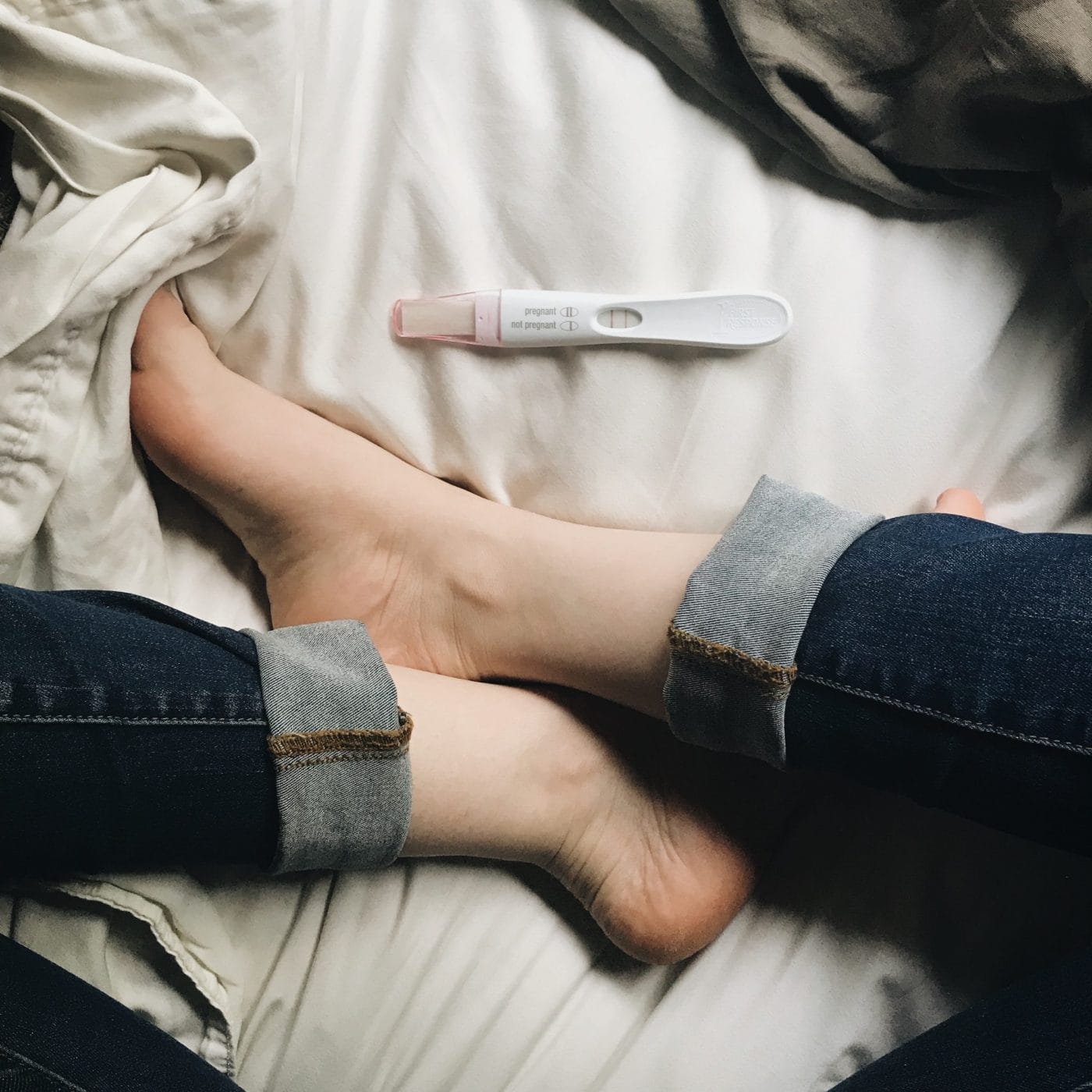 I didn’t wait three months to announce my pregnancy woman sits in bed and looks at pregnancy test - announced pregnancy early