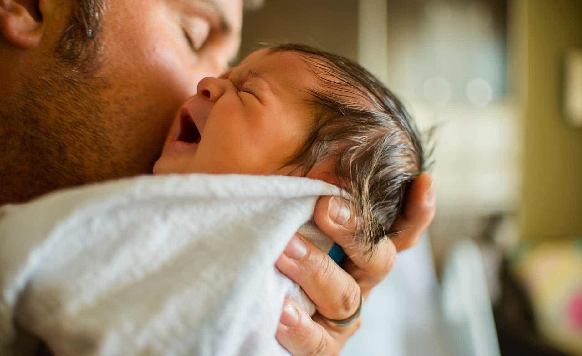 Seeing my husband become a father made me fall in love even more dad kissing newborn baby