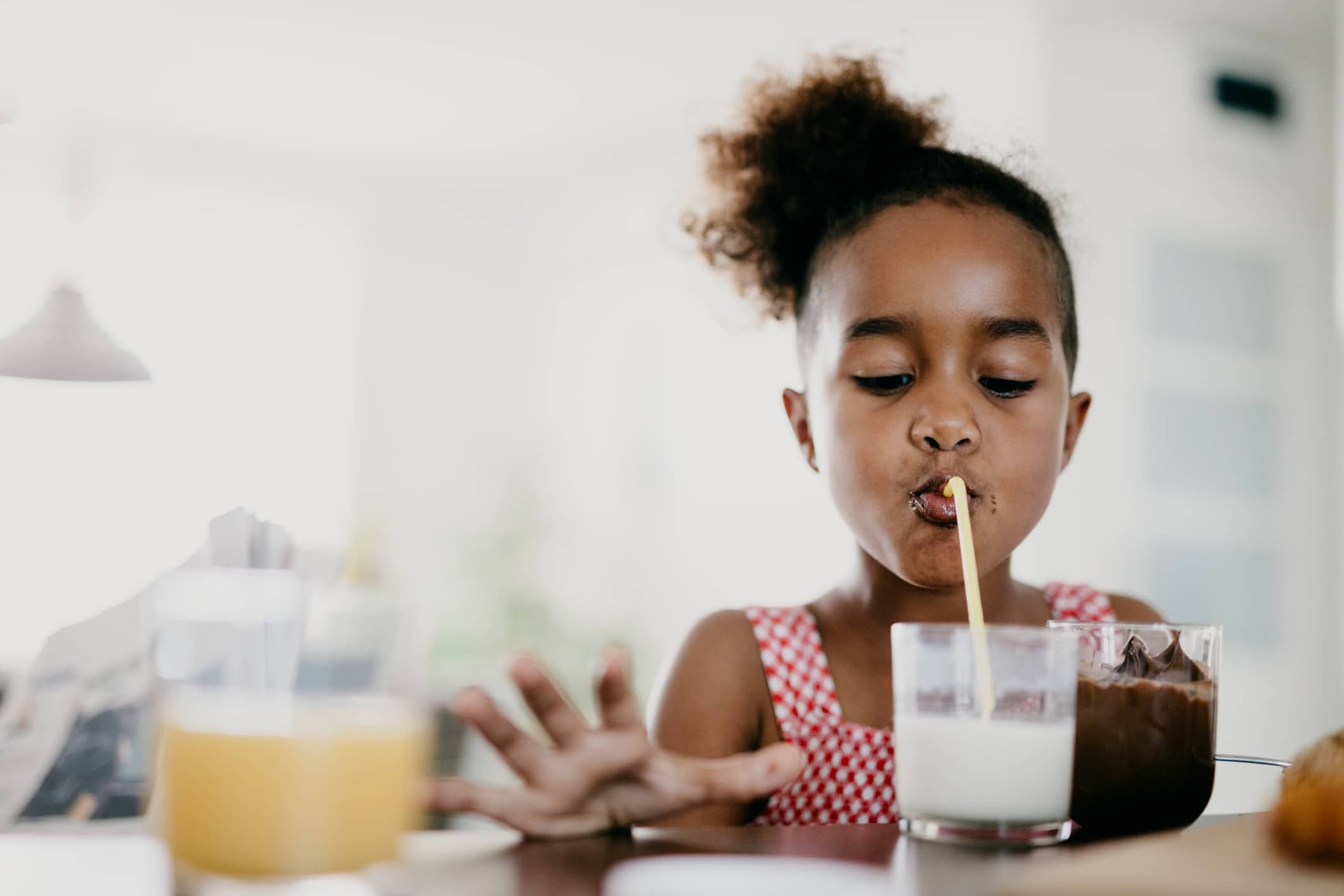 Does your child need a multivitamin? Here’s what the experts say young girl drinking milk through a straw