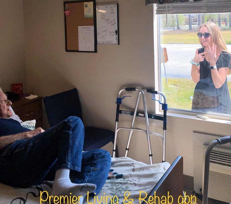 This touching moment between a granddaughter and her quarantined grandfather is what we need right now woman talking to old man outside a window