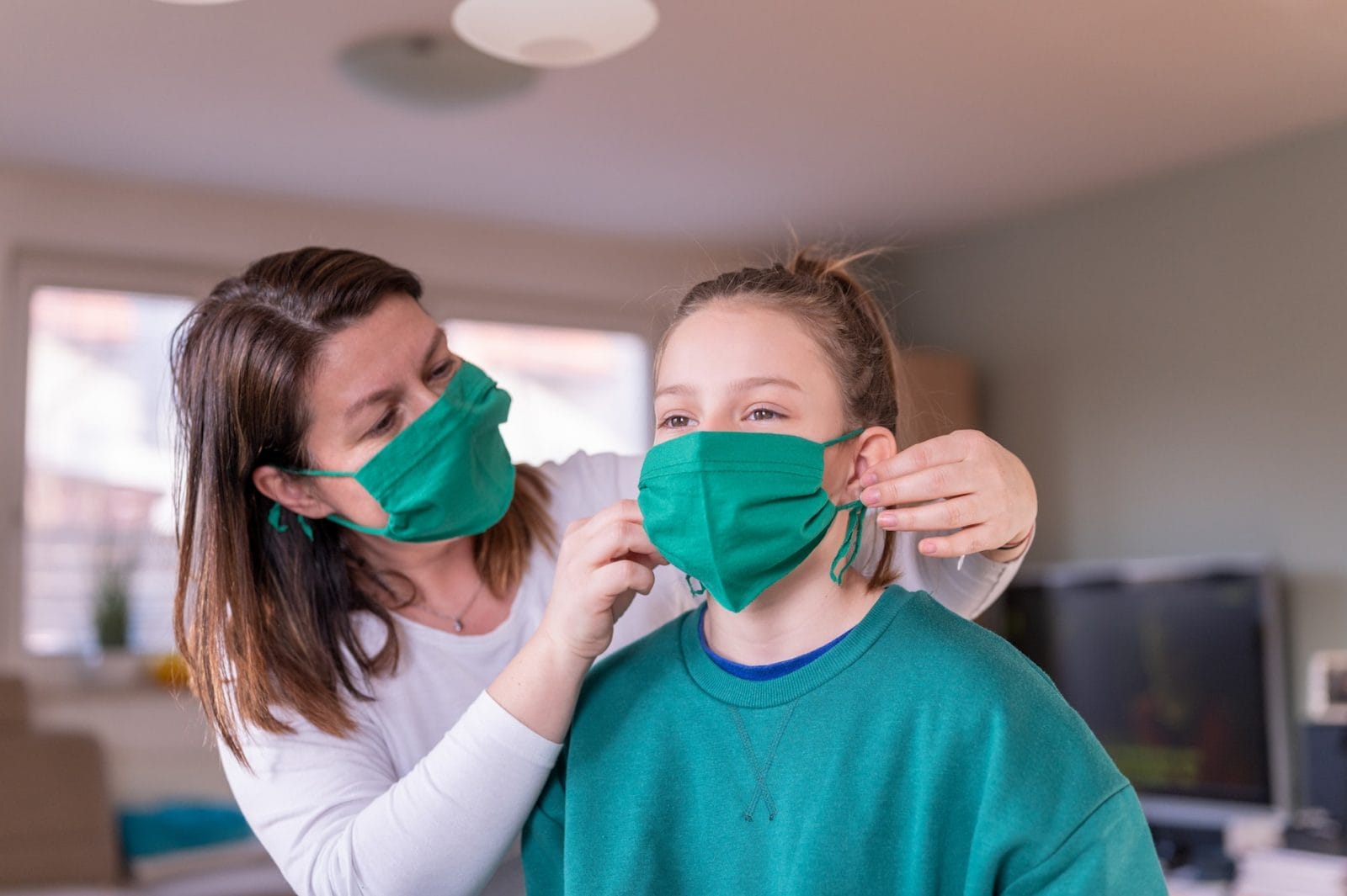 Here’s how to make DIY face masks with what already you have at home mom putting a mask on her daughter