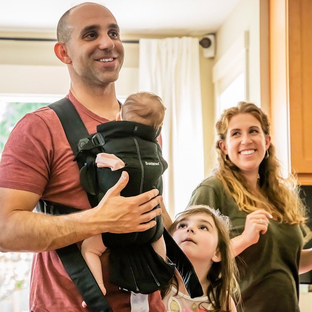 Microsoft is giving an extra 12 weeks of paid leave to parents because of coronavirus dad wearing baby while toddler and mom stand behind