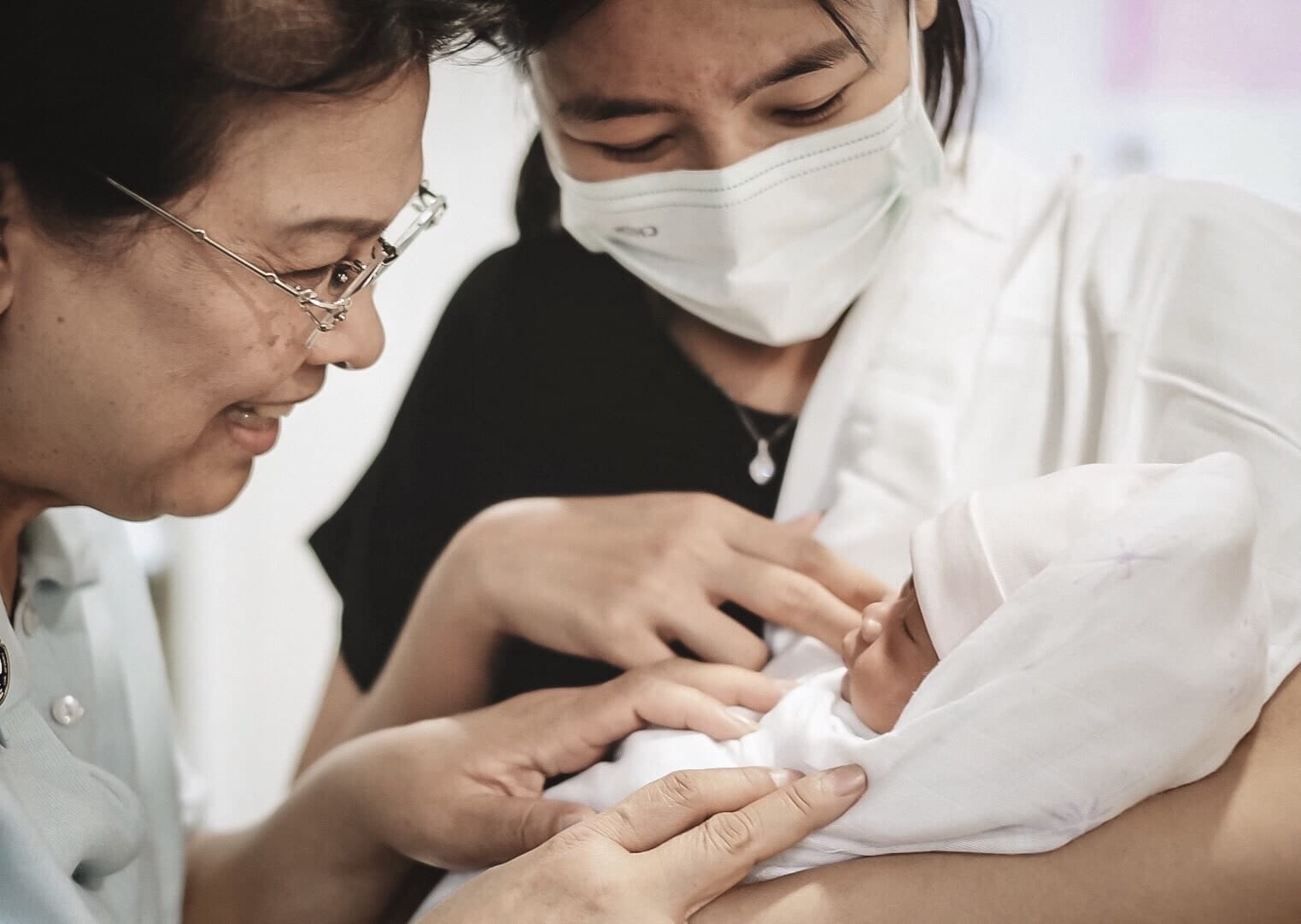 Pregnant women about to give birth need COVID-19 testing mom and grandma looking at newborn while wearing a mask