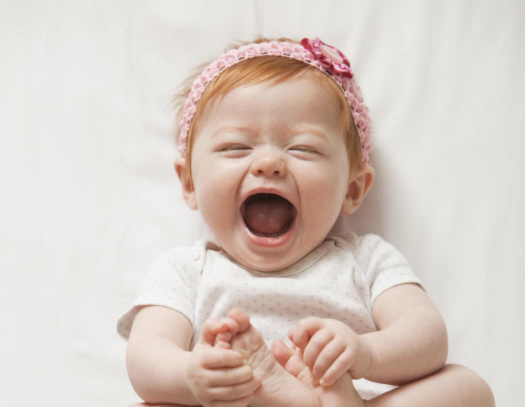 5 reasons May babies are special happy baby touching toes - Motherly's reasons May babies are special