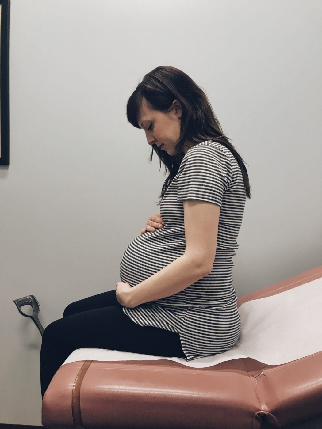 I mourn the pregnancy experience I could have had pregnant woman holding belly at a doctors office