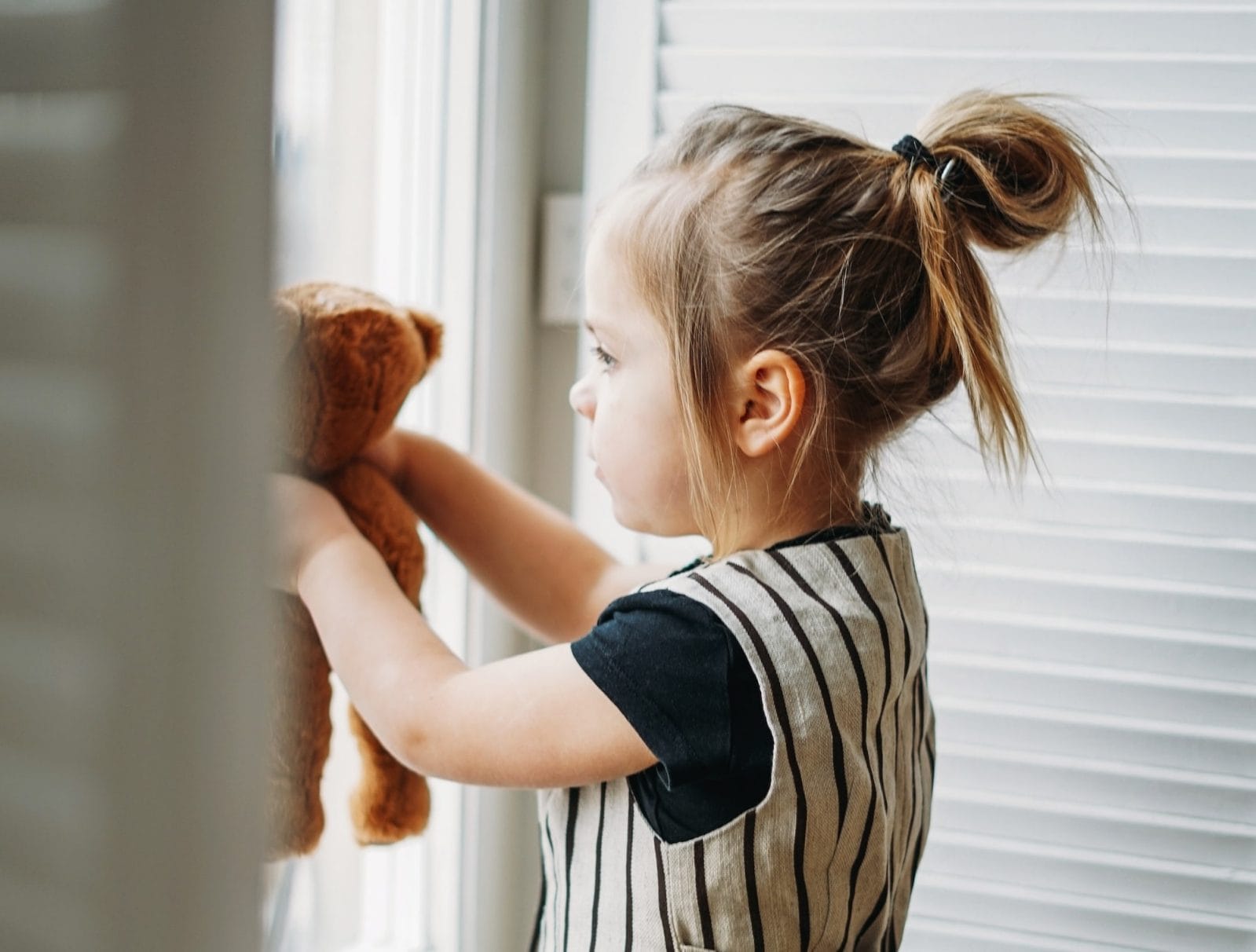 How to help kids be resilient through the pandemic child and her stuffed animal looking out window
