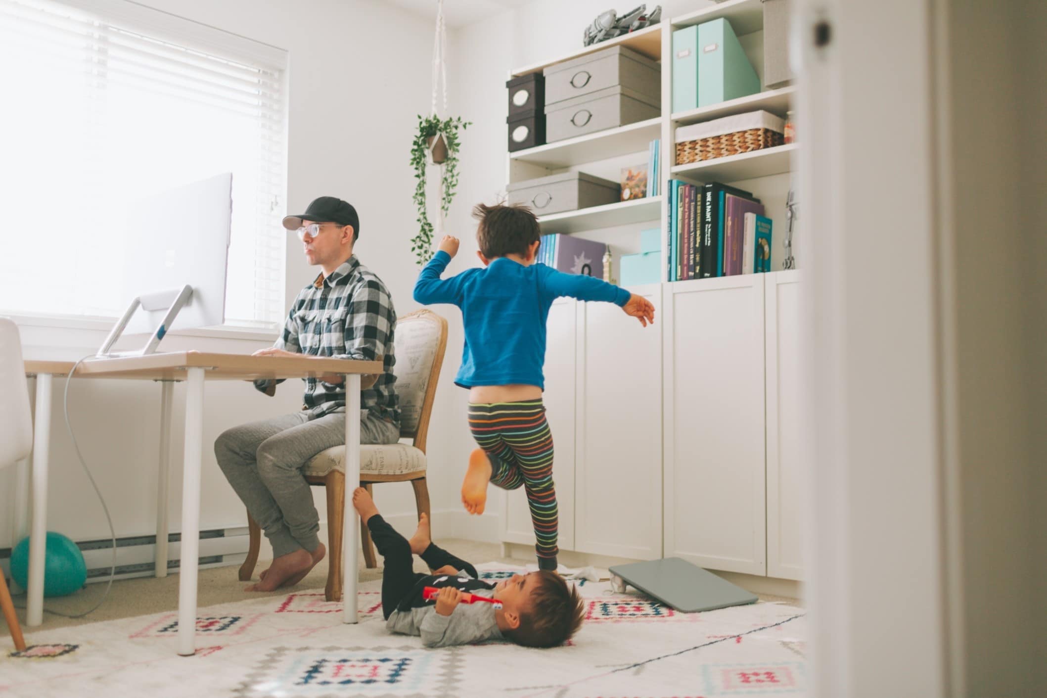 3 strategies to try when work & parenting collide under quarantine dad working while child plays behind him