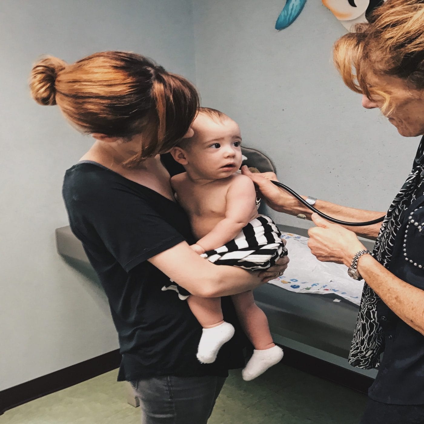 Childhood vaccinations are dropping during the pandemic mom holding child at the pediatrician