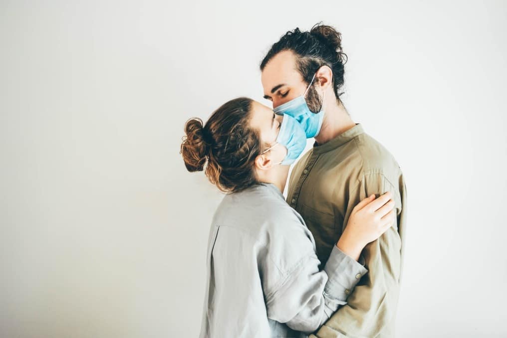 Should I try to get pregnant during the coronavirus pandemic? couple kissing through masks