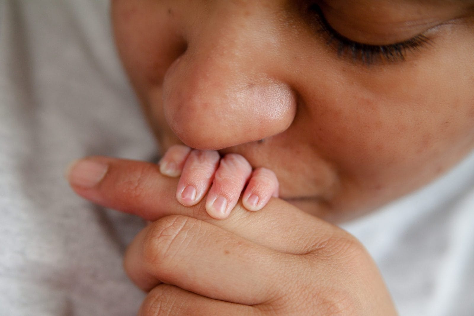The truth about raising a newborn in quarantine mom kissing baby hand
