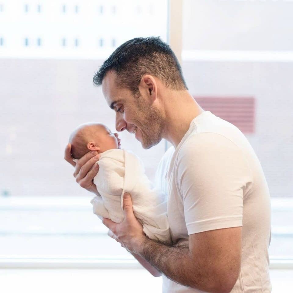 Dear mother-in-law, thank you for raising an incredible man father holding a swaddled newborn baby to his face