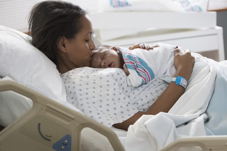 Having more Black doctors and midwives could be the key to reducing Black maternal mortality rates mother holding newborn in hospital- black doctors
