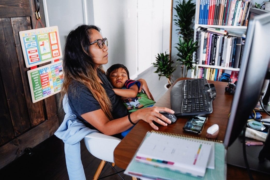 The pandemic is forcing 74% of moms to consider quitting their jobs woman working while holding baby