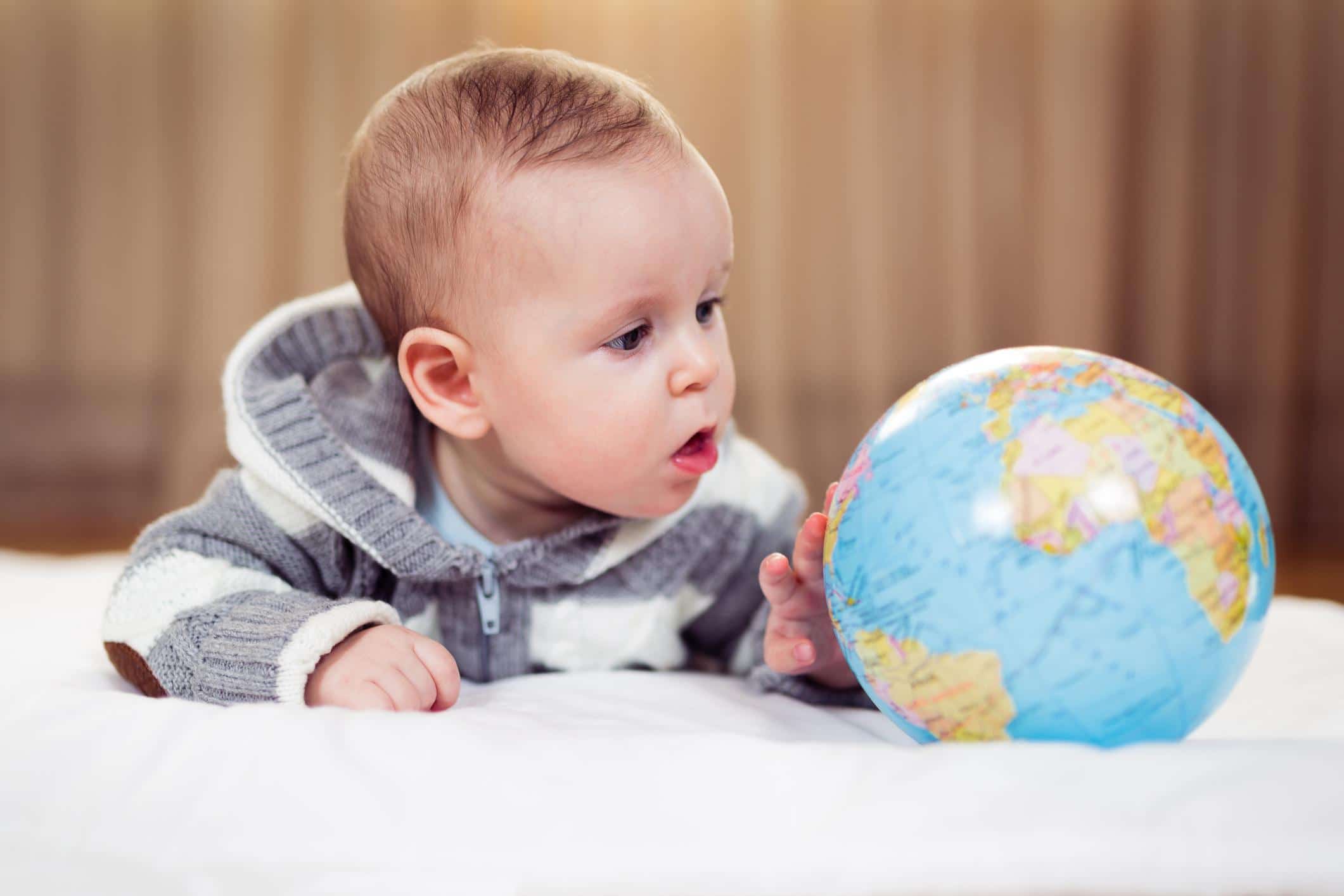 Top baby names inspired by American geography baby looking at a globe