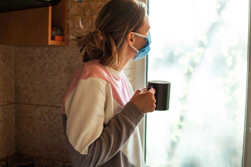 What to do if you get COVID-19, from an ER doctor who lived it woman wearing a mask looking outside a window