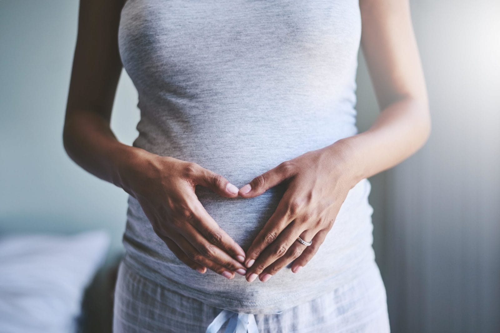 I have a bicornuate uterus, but the toughest part of my pregnancy was being scared about it pregnant woman forming a heart with her hands in front of her pregnant belly