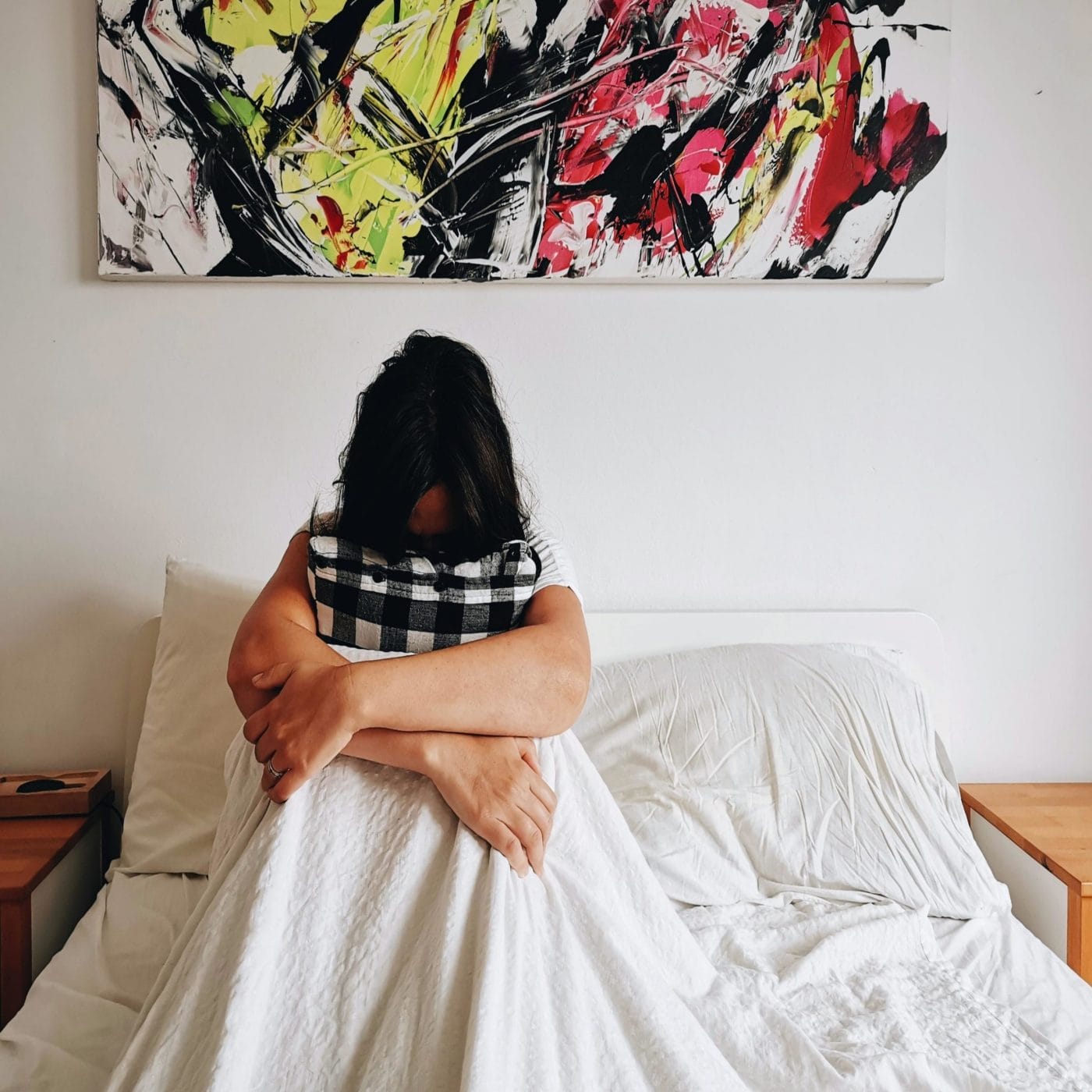 A mom was arrested for leaving her kids alone while she worked—here’s why we need to talk about it woman with head in knees in a bed
