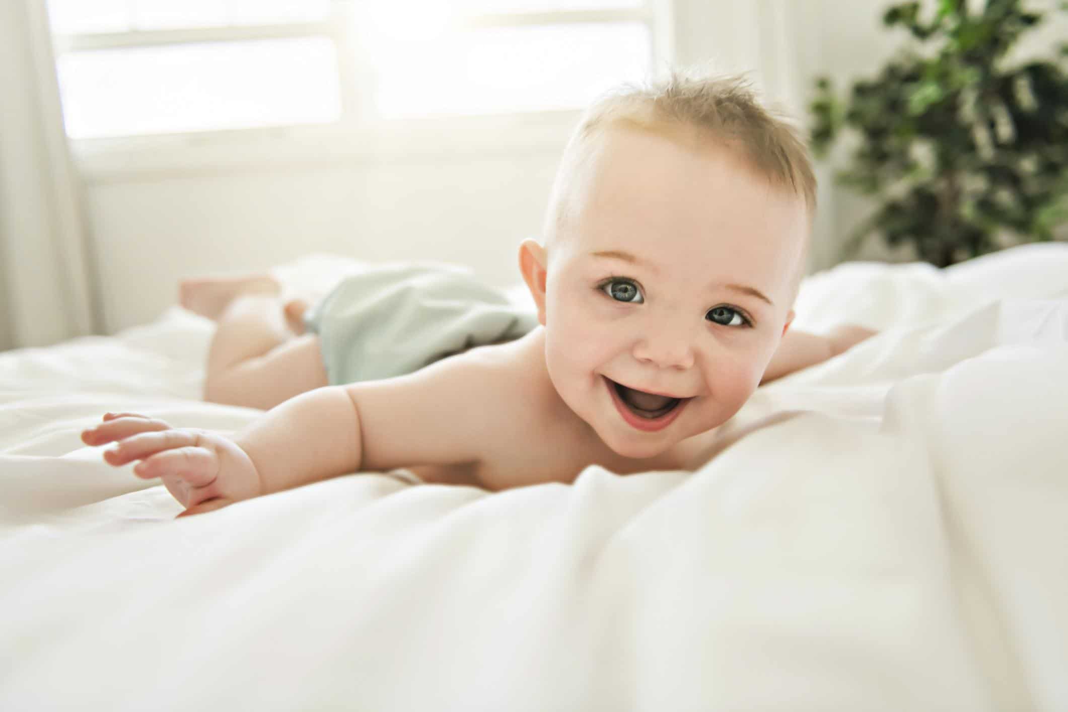 A beginner’s guide to cloth diapering baby wearing a cloth diaper laying on a bed