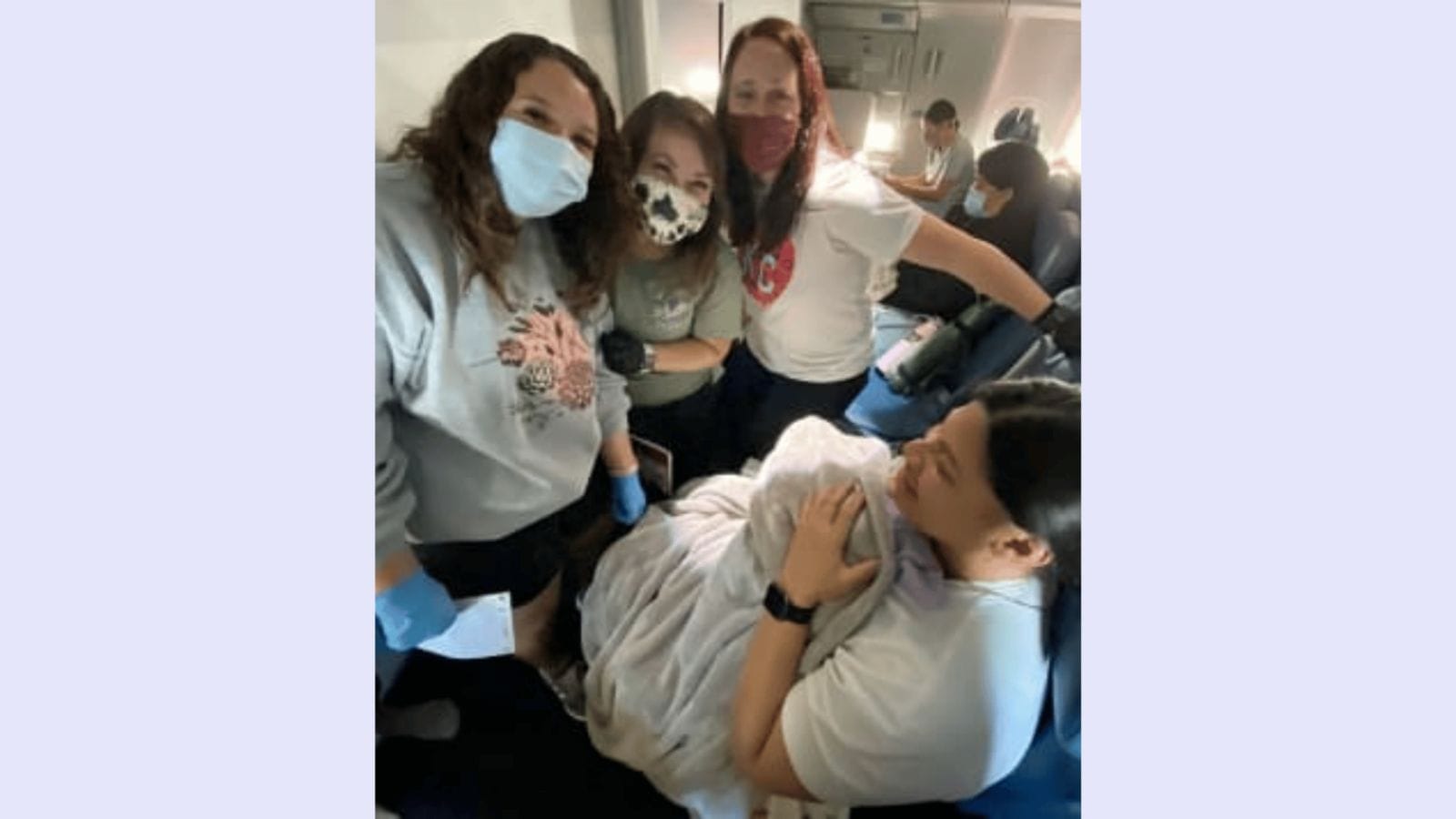 A woman unaware she was pregnant gives birth on airplane mother holding newborn baby on a plane