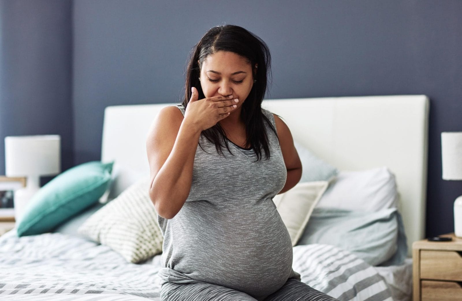 4 lies I believed about morning sickness—before I had it myself woman covering her mouth while pregnant