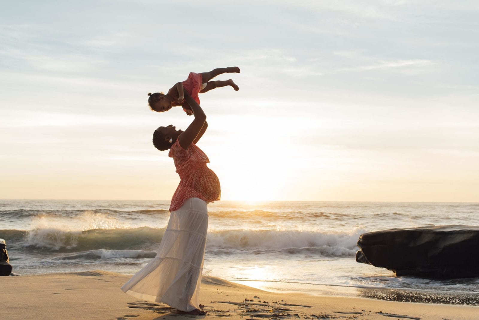 Climate change harms moms and babies—but we can do something about it right now mom throwing daughter above head on the beach