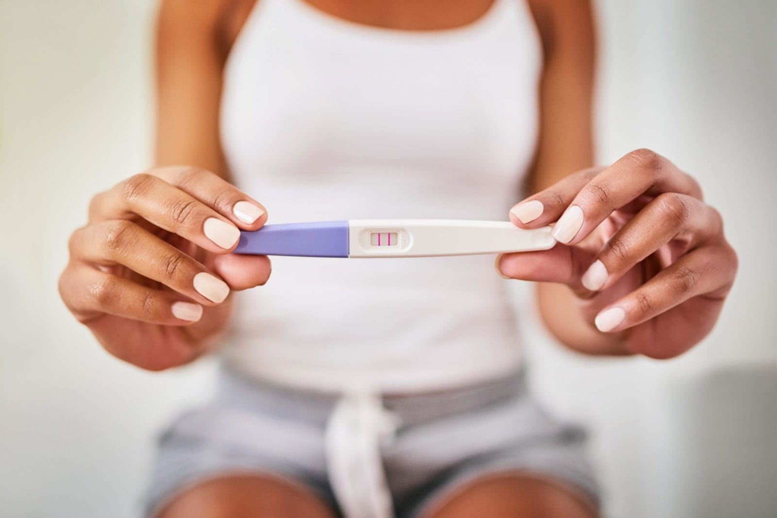 What causes a false positive pregnancy test? woman holding a positive pregnancy test - but what causes a false positive pregnancy test