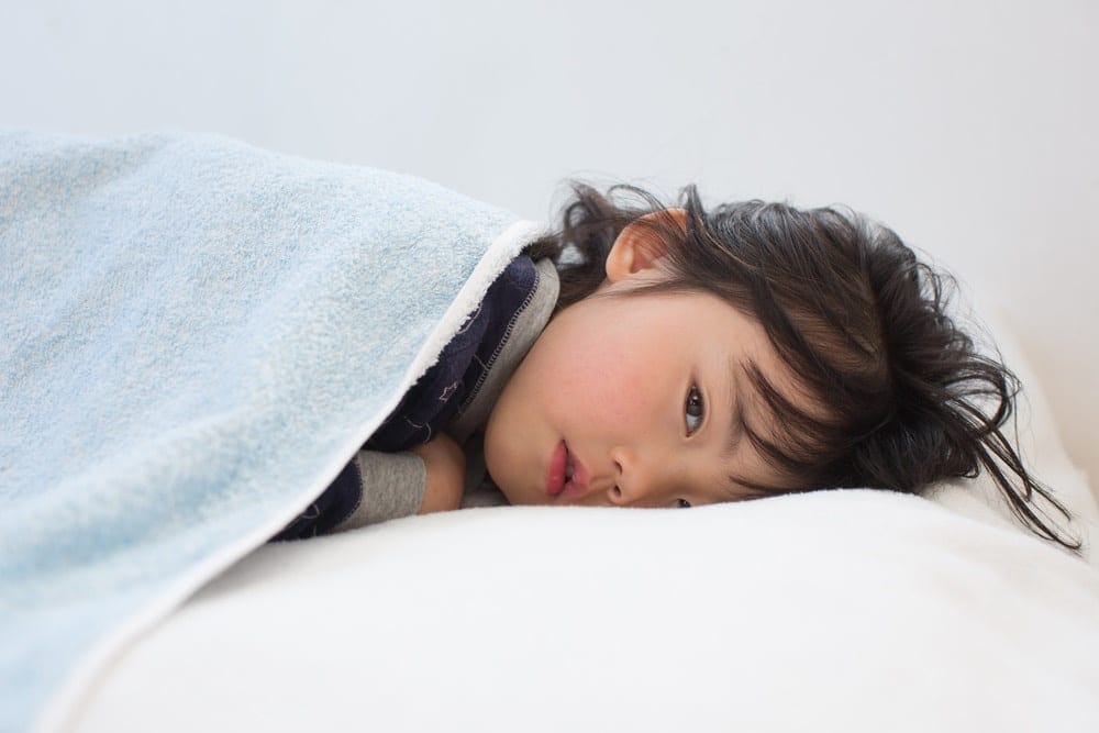 The unexpected flu symptom every parent should be aware of little girl lying in bed under covers