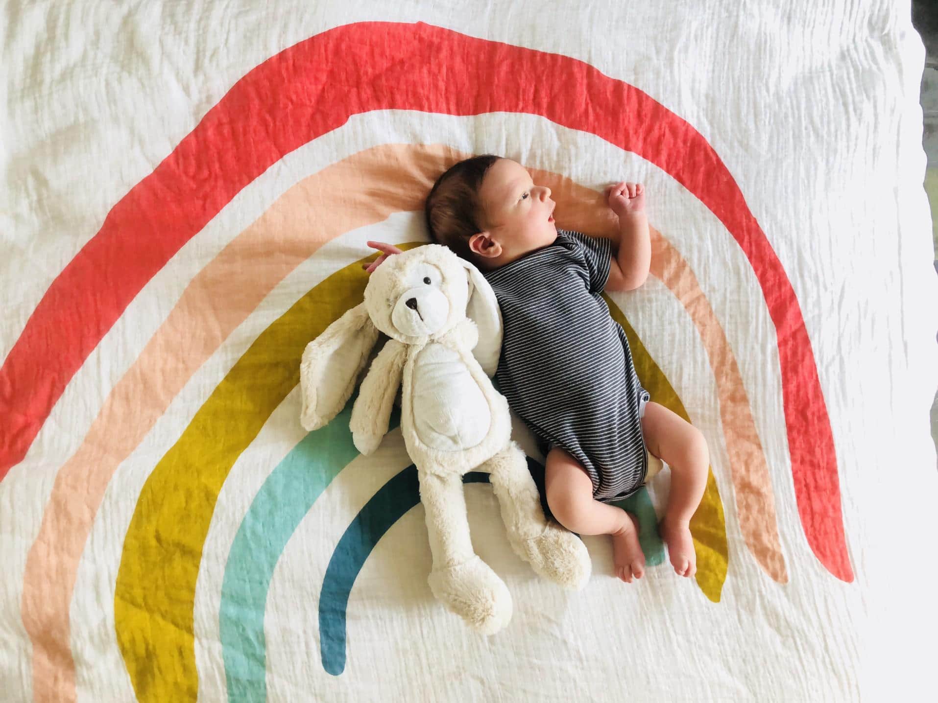 50 meaningful names for your rainbow baby baby laying on a rainbow blanket- rainbow baby names