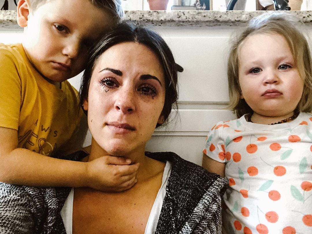 This mama is going viral for perfectly describing the highs + lows of motherhood selfie of mom crying surrounded by two kids