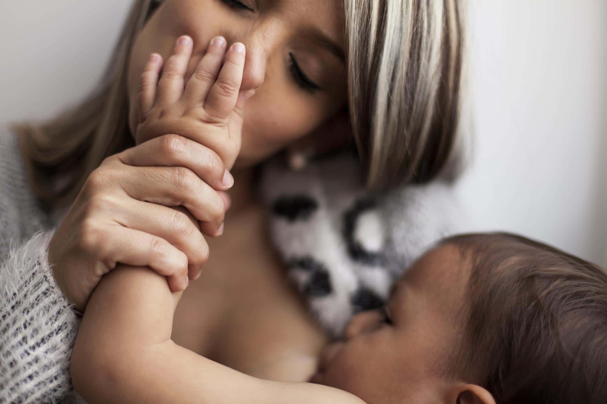 “Forever chemicals” can be found in breast milk, but you can limit your exposure right now mom kissing baby's hands while breastfeeding