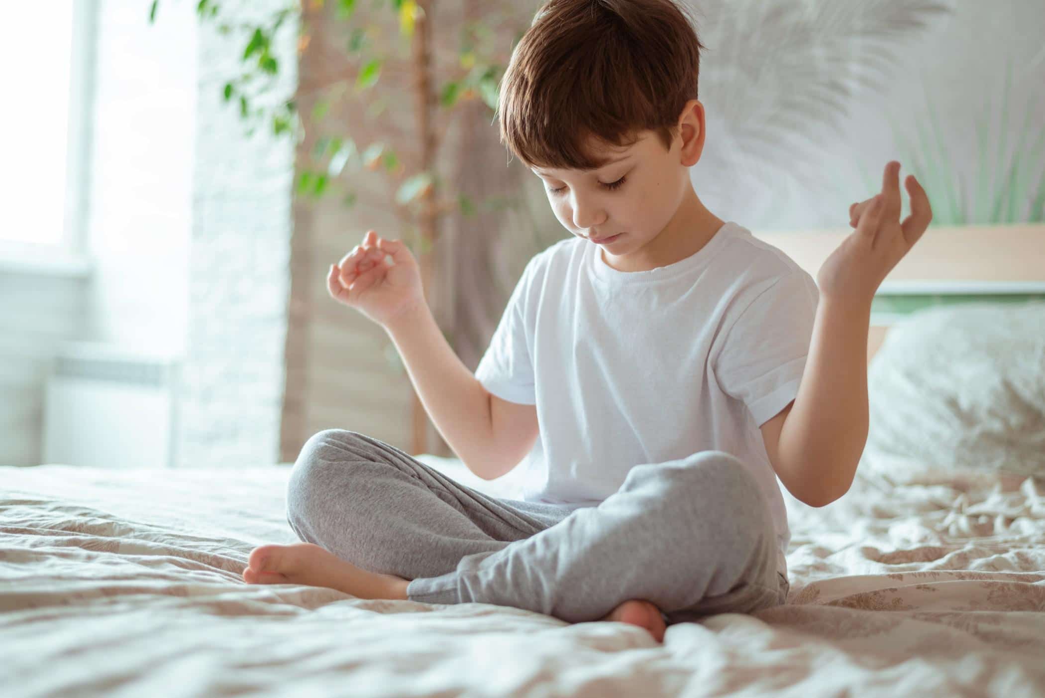 Mindfulness training helps kids sleep longer, study reveals little boy doing meditation