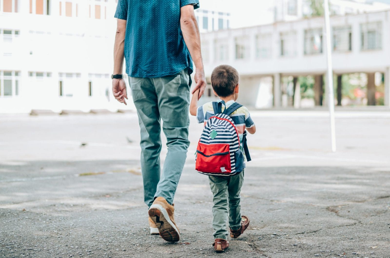 11 encouraging phrases to tell your kids on the first day of school dad and son holding hands walking into school- encouraging phrases for kids