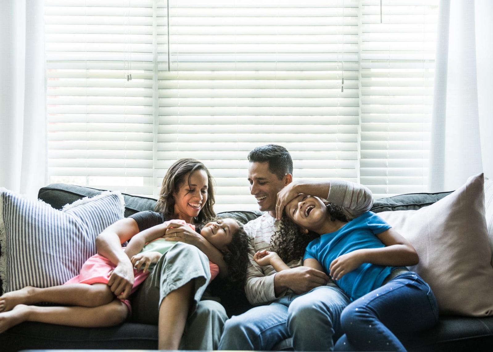 Why ‘lazy parenting’ is actually a recipe for happy families mom dad and two kids on couch- lazy parenting