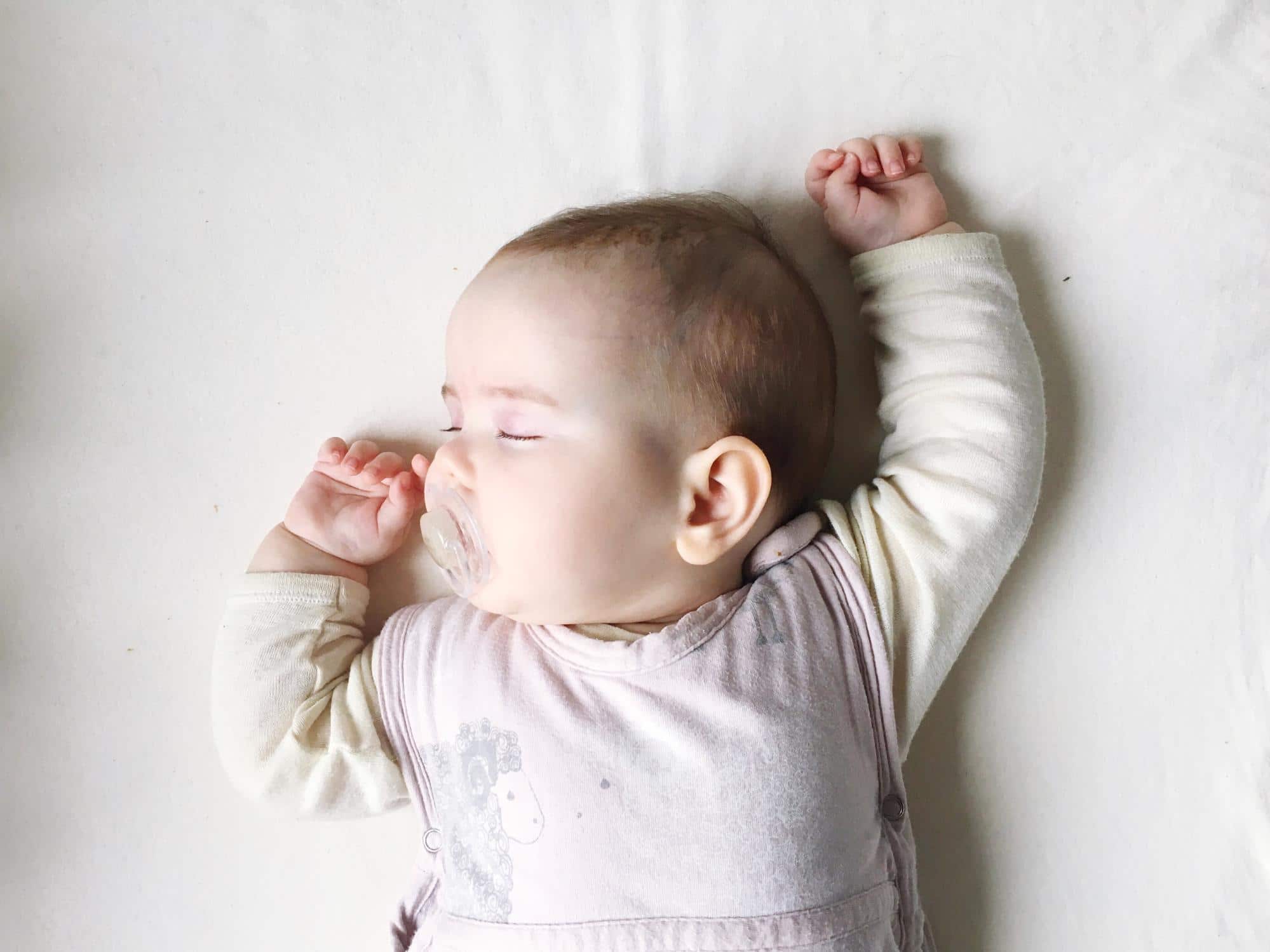 How much sleep does a seven-week-old baby need? seven-week-old baby sleeping with arms above its head