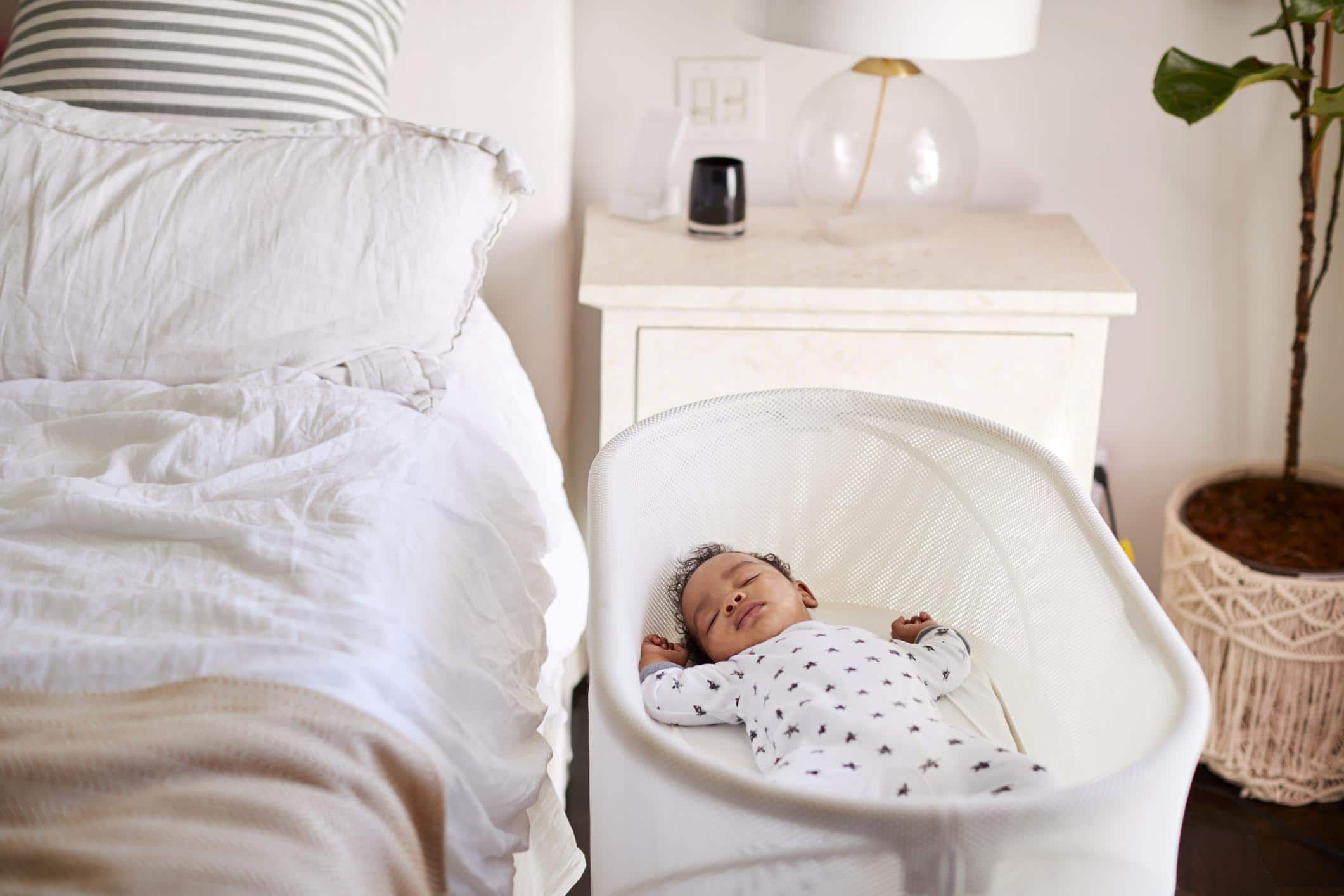How much sleep does a two-week-old baby need? baby sleeping in a bassinet close to a bed