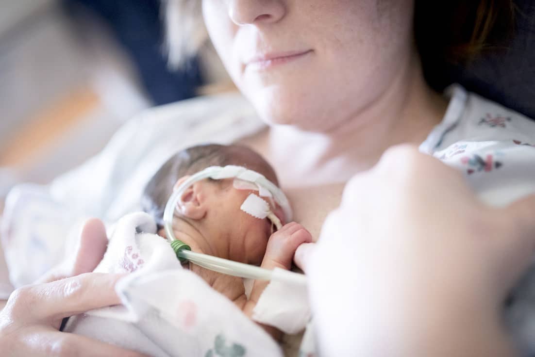 I’m a survivor. I’m a NICU mama. mom holding baby in the NICU