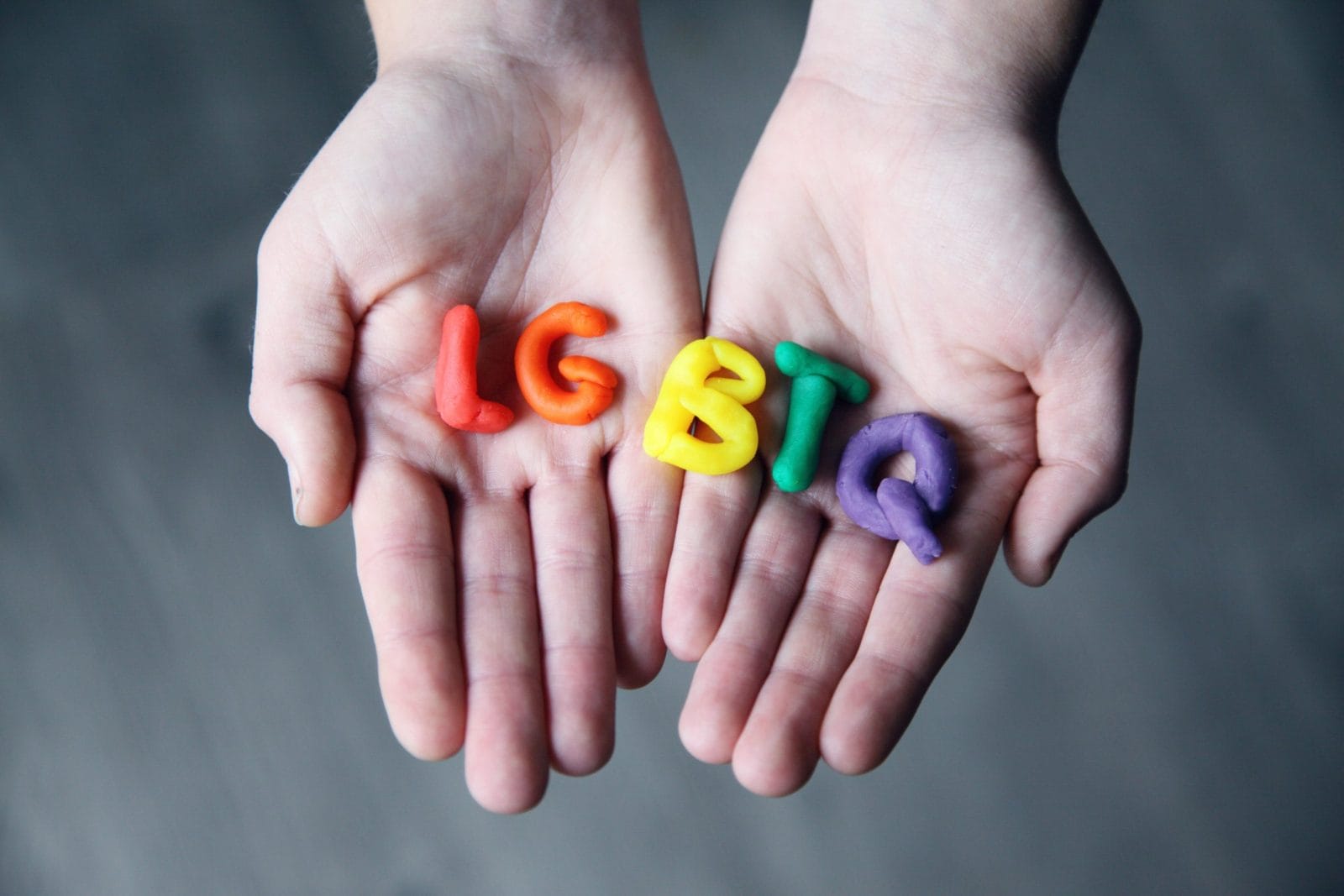 How one company is making a huge difference for LGBTQ youth hands holding LGBTQ in clay