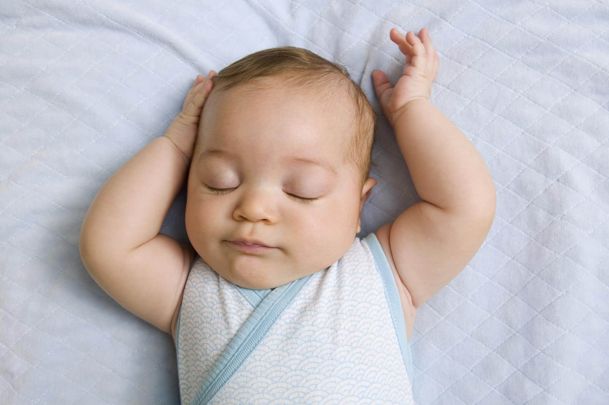 How much sleep does a six-month-old baby need? six-month-old baby sleeping with arms above its head