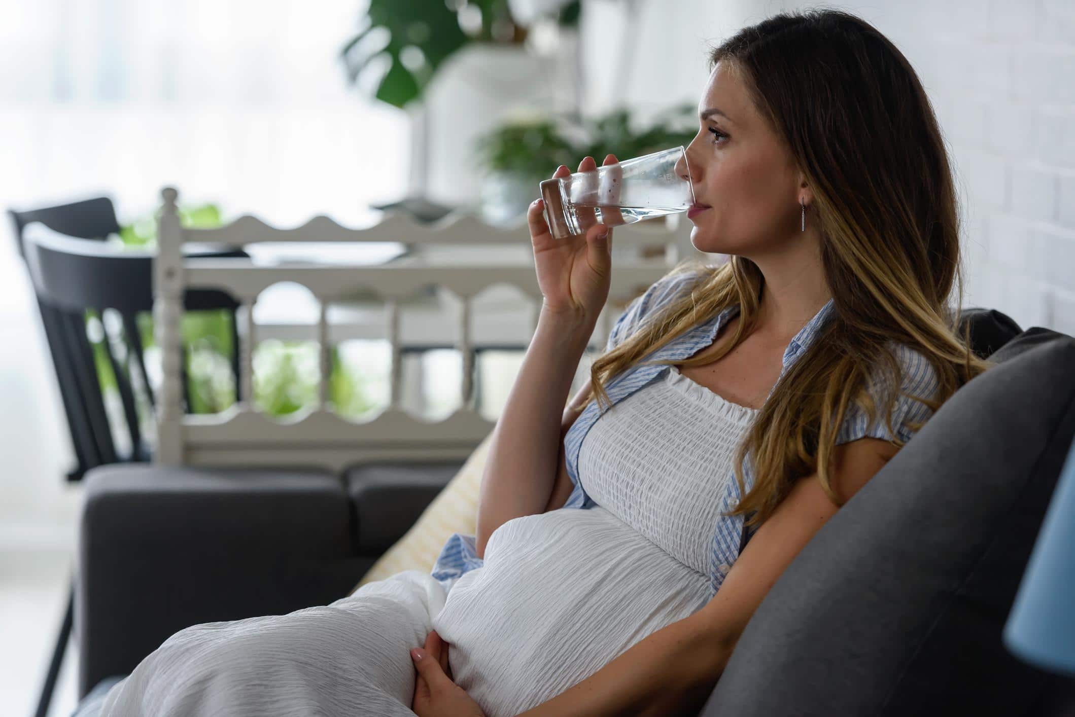 Experts warn that acetaminophen is NOT considered safe in pregnancy woman holding belly drinking water