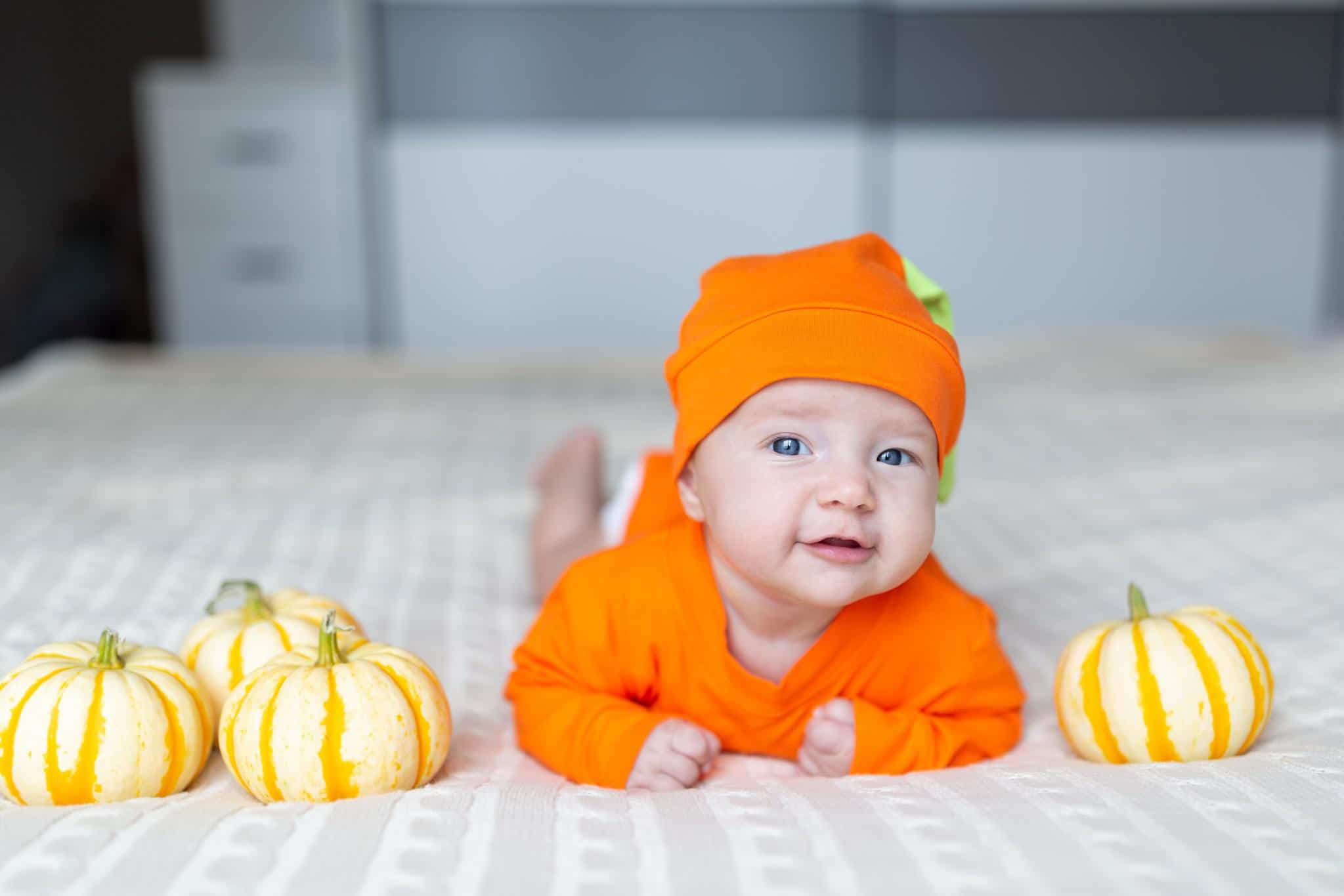 20 October baby names that are boo-tiful baby dressed up like a pumpkin laying beside baby pumpkins - october baby names