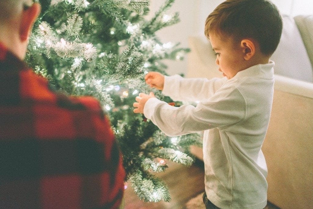 How to have a very merry Christmas with kids for $200 or less—seriously a child standing next to a christmas tree