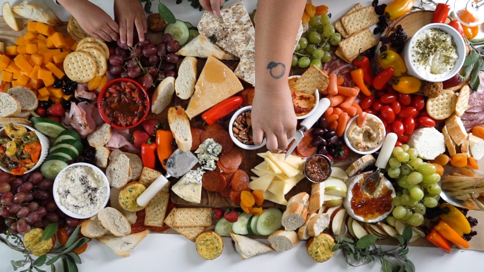 How to create a healthy & delicious grazing table for the holidays woman picking off a charcuterie board