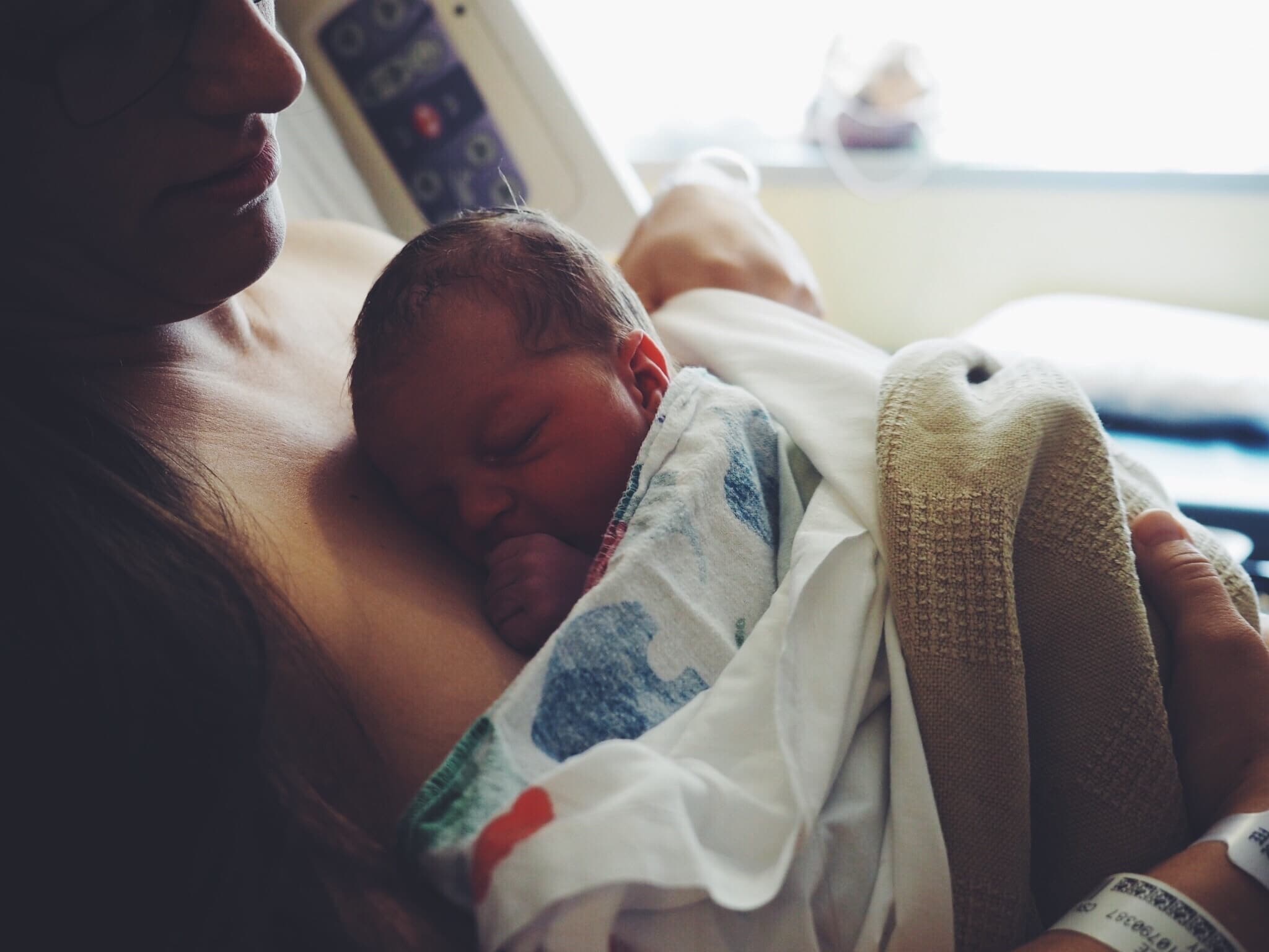 This viral post about the Fourth Trimester is exactly what new mamas need right now mom holding baby in a hospital bed