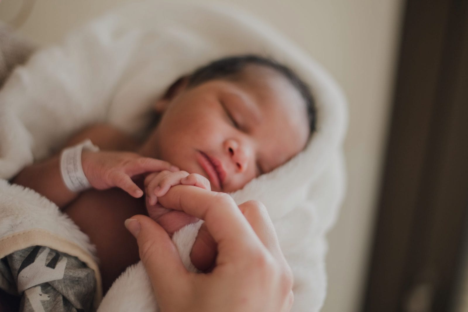 Sorry, you can’t meet our baby yet newborn baby wrapping her finger around her moms finger
