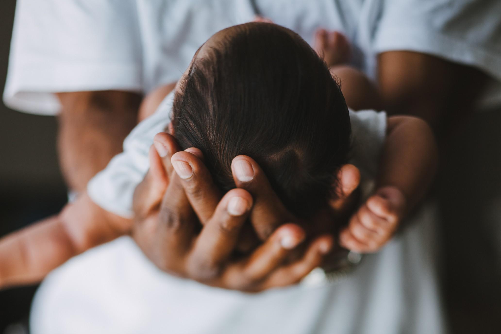1-month-old baby milestones mom holding baby's head in her palms, celebrating 1-month milestones