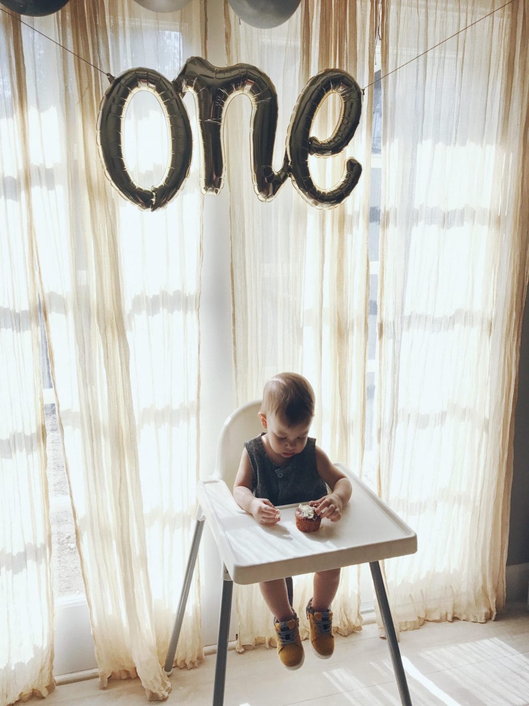 12-month-old baby feeding schedule & expert advice 1 year old baby with birthday balloons over his head - 12-month-old baby feeding schedule