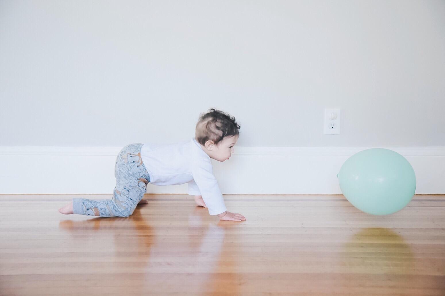 baby crawling towards balloon, one of the 10-month milestones