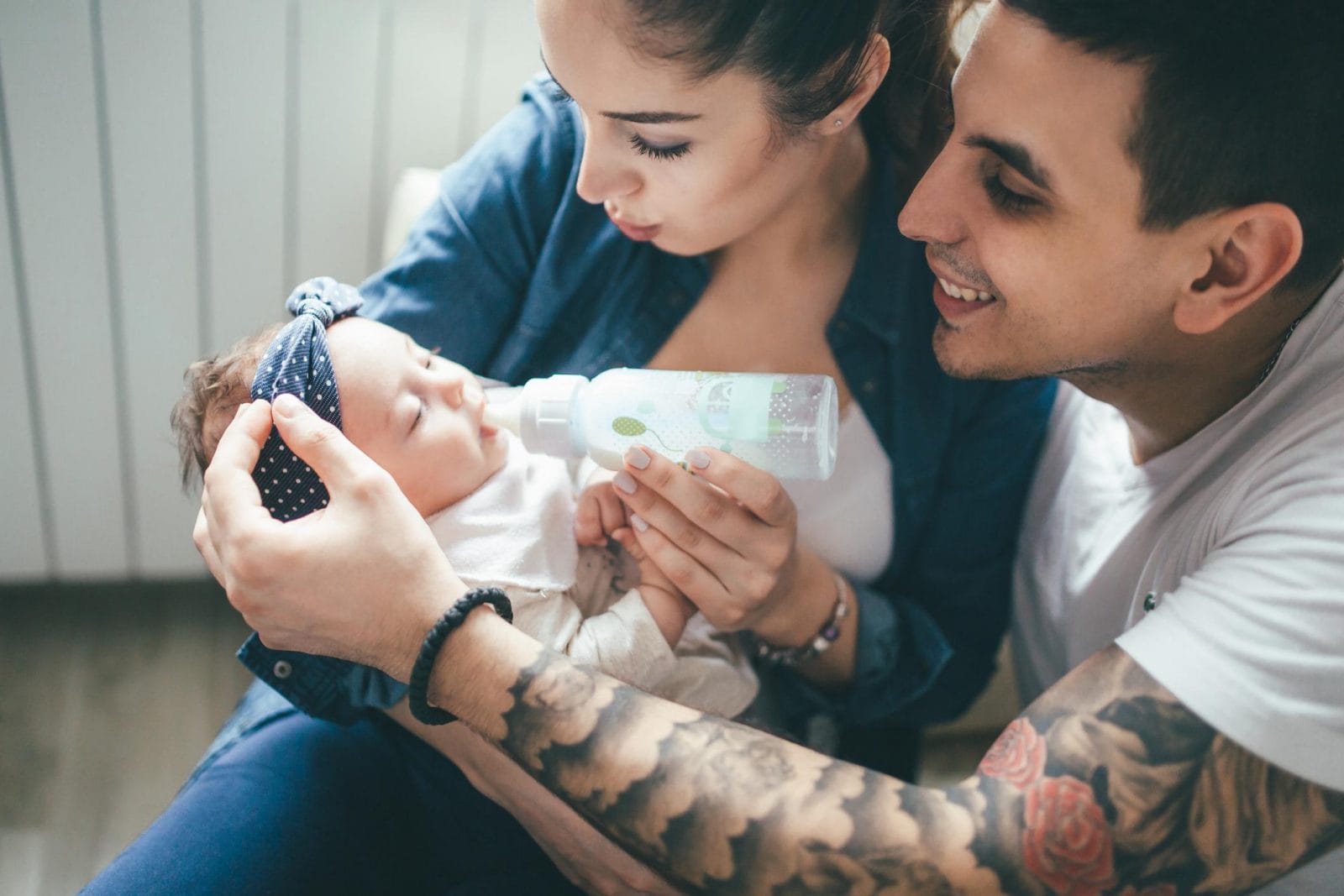 11-week-old baby feeding schedule & amounts parents cuddling a baby - 11-week-old baby feeding schedule